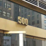 Large brass colored number 500 on the front of the building of Pearl Studios location