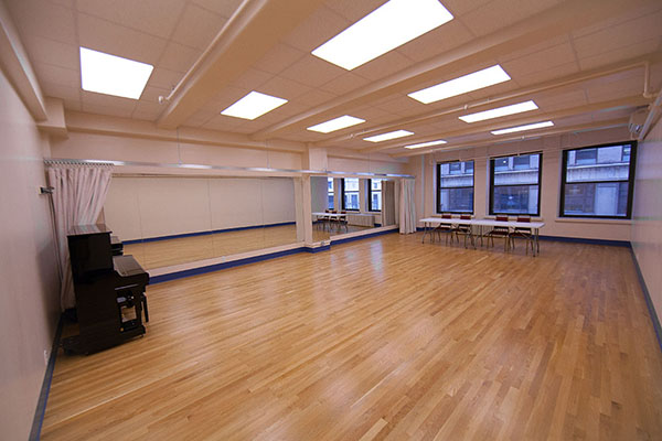 Studio rental room with wood floors, full wall of mirros, piano and acoustic curtain